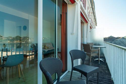 a balcony with chairs and a table on a building at Britania - Appt pour 6 proche plage in Bénodet