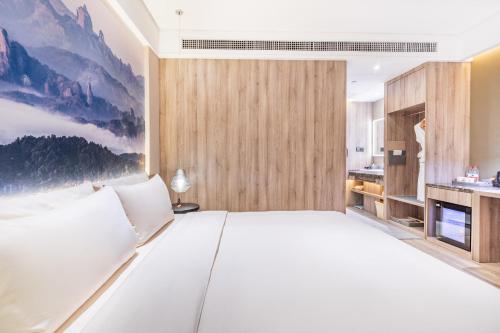 a large white bed in a room with a kitchen at Atour Hotel Guangzhou Jiangtai Road Station in Guangzhou