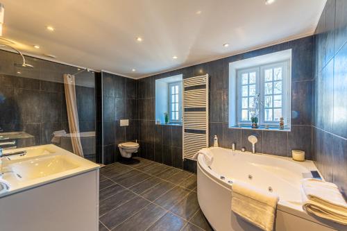 een badkamer met een bad, een wastafel en een toilet bij Domaine de Jade - Maison de Maître pour 15 in Châtillon-la-Borde