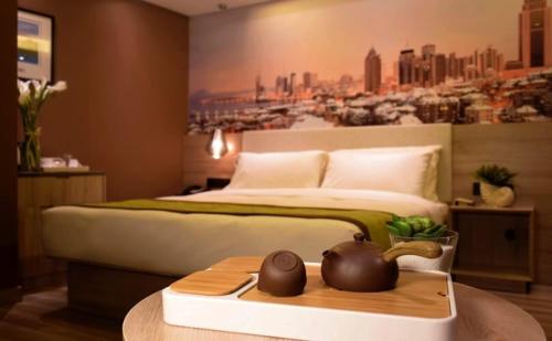 a bedroom with a large bed with a painting on the wall at Atour Hotel Qingdao Olympic Sailing Center May Fourth Square in Qingdao