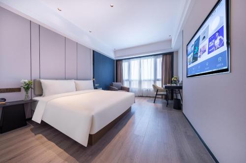 Cette chambre comprend un grand lit et une télévision à écran plat. dans l'établissement Atour X Hotel Ningbo Railway Station Liuting Street, à Ningbo