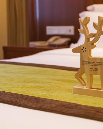 a wooden figurine of a reindeer on a bed at Atour Hotel Wangfujing Ave Xinjiekou Nanjing in Nanjing
