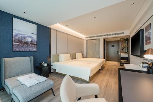 um quarto de hotel com uma cama e uma cadeira em Atour Hotel Qingdao Central Business District University of Science and Technology em Qingdao