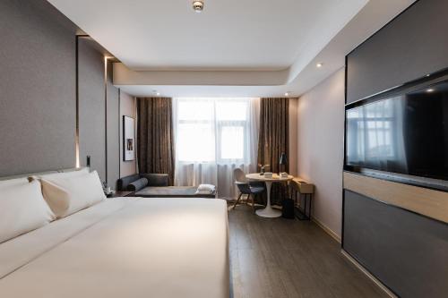 a hotel room with a large bed and a television at Atour Hotel Suzhou Guanqian Street in Suzhou