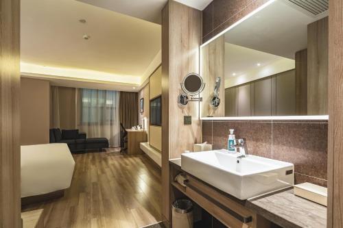 a bathroom with a sink and a mirror at Atour Hotel Qingdao Olympic Sailing Center May Fourth Square in Qingdao