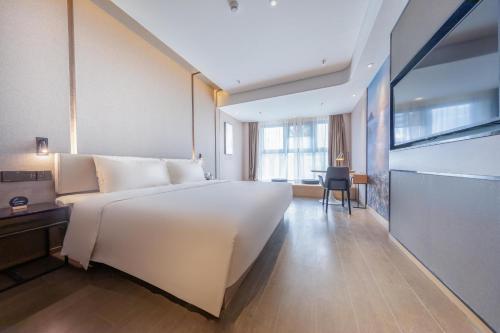 uma grande cama branca num quarto com uma secretária em Atour Hotel Shenzhen Shajing International Convention and Exhibition Center em Bao'an