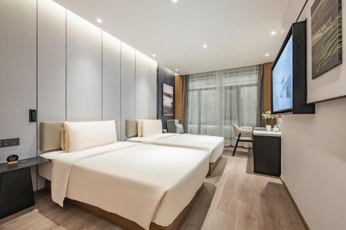 成都市にあるAtour Hotel Chengdu Taikoo Li Chunxi Road Pedestrianのベッド2台とデスクが備わるホテルルームです。