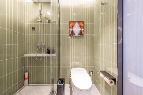 uma casa de banho com azulejos verdes, um WC e um chuveiro em Atour Hotel Beijing Tiananmen Wangfujing Pedestrian em Pequim