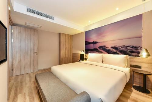 a bedroom with a white bed and a painting on the wall at Atour Hotel Dalian Development Zone Jinma Road in Dalian