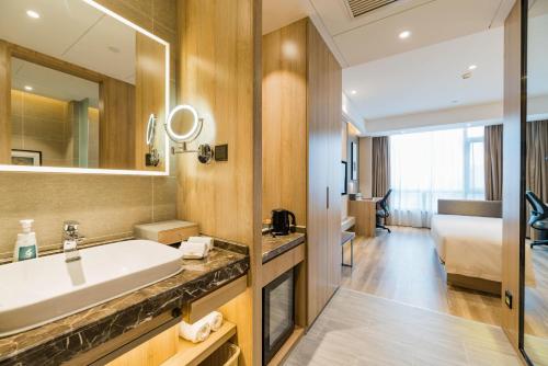 łazienka z umywalką i dużym lustrem w obiekcie Atour Hotel Hefei South Railway Station w mieście Hefei