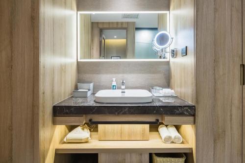 a bathroom with a sink and a mirror at Atour Hotel Qingdao Fuzhou Road Sakura Town in Qingdao