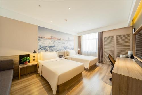 ハルビン市にあるAtour Hotel Harbin Convention and Exhibition Center Nongkenのベッド2台とデスクが備わるホテルルームです。