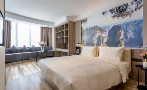 Atour Hotel Changsha IFC Center في تشانغشا: غرفة نوم بسرير كبير وأريكة