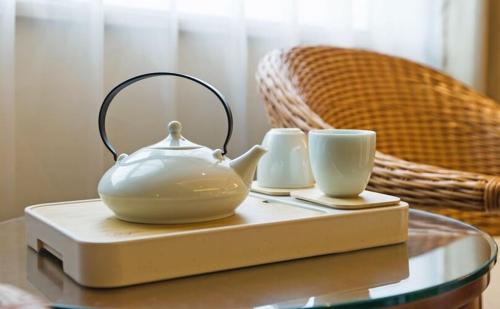 una tetera y dos tazas en una mesa de cristal en Atour Hotel Wangfujing Ave Xinjiekou Nanjing, en Nanjing