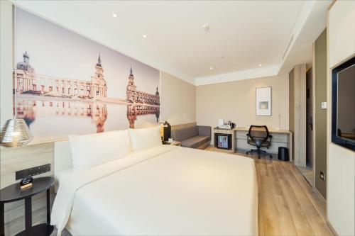 a bedroom with a large white bed and a tv at Atour Hotel Harbin Convention and Exhibition Center Nongken in Harbin