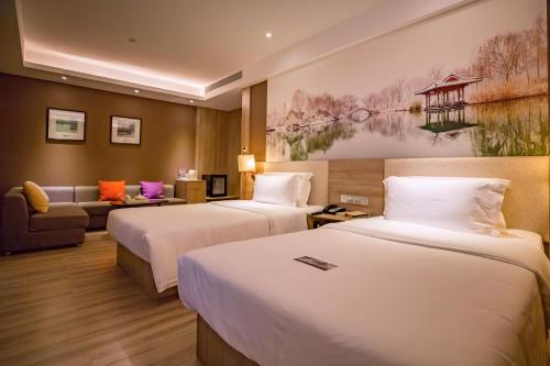 済南市にあるAtour Hotel Jinan High-tech Wanda Plaza Tiancheng Roadのベッド2台とソファがあるホテルの部屋