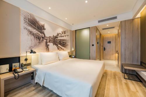 um quarto com uma grande cama branca e uma televisão em Atour Hotel Hefei South Railway Station em Hefei