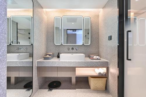 a bathroom with two sinks and two mirrors at Atour S Hotel Beijing Sanlitun Guoan in Beijing