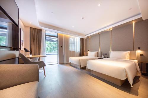a hotel room with two beds and a couch at 厦门火车站明发广场亚朵酒店 in Xiamen