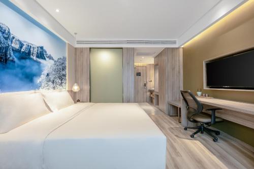 a bedroom with a large bed and a desk with a television at Atour Hotel Changsha International Covention Centre South Railway Station in Changsha