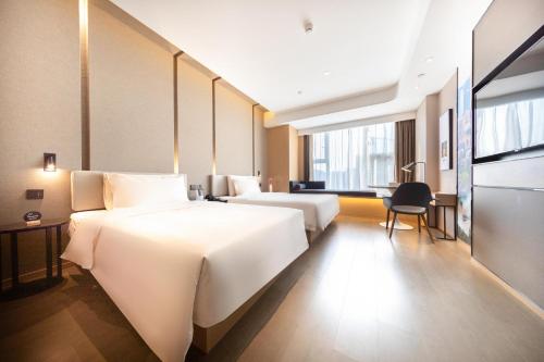 a hotel room with two beds and a desk at Atour Hotel South Jinan Industrial Road CBD in Jinan