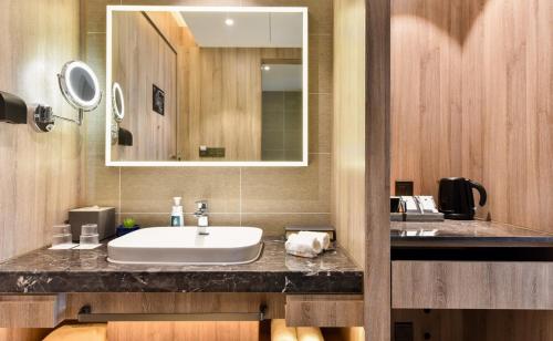 bagno con lavandino e specchio di Atour Hotel Capital Airport Beijing a Pechino
