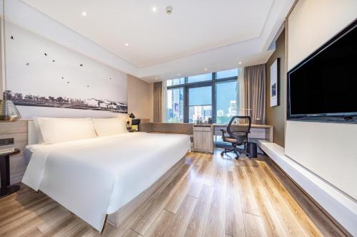 a hotel room with a large bed and a flat screen tv at Atour Hotel Three Lanes and Seven Alleys Fuzhou in Fuzhou