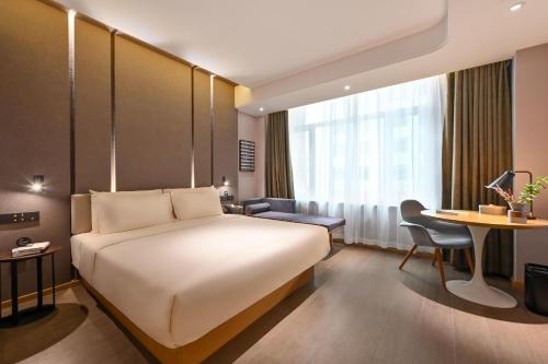 a hotel room with a large bed and a desk at Atour Hotel Changchun Automobile Development Zone in Changchun