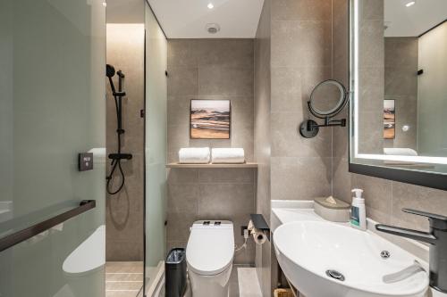 uma casa de banho com um WC, um lavatório e um espelho. em Atour Hotel Shanghai Center Lujiazui em Xangai