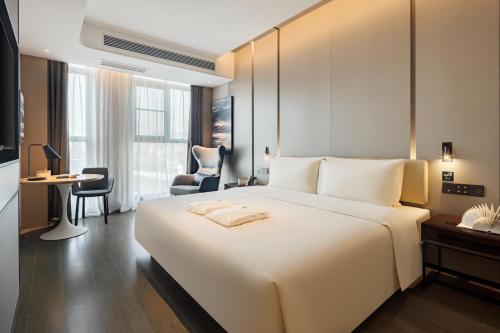 Atour Hotel Chongqing Qibo Center في تشونغتشينغ: غرفة في الفندق مع سرير أبيض كبير ومكتب