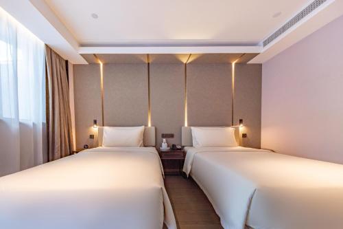 two beds in a hotel room with lights on the wall at 厦门火车站明发广场亚朵酒店 in Xiamen