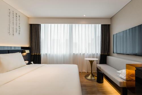 a hotel room with a bed and a couch at Atour S Hotel Shanghai Lujiazui Financial Center in Shanghai