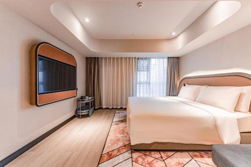 a hotel room with a bed and a flat screen tv at Atour Light Hotel Chunxi Road Subway Station Taikoo Li Chengdu in Chengdu