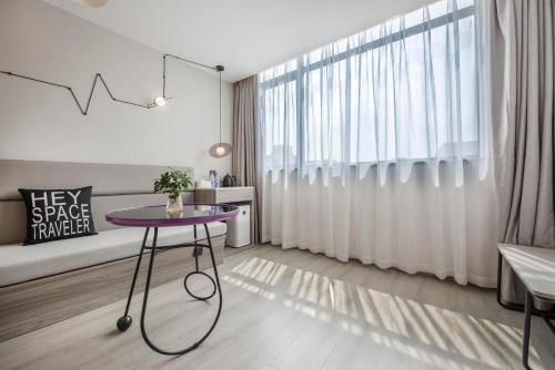 a living room with a purple table in front of a window at Atour Hotel Zhuhai Gongbei Port Fuhuali CBD in Zhuhai