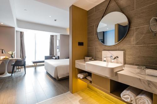 a bathroom with a bed and a sink and a mirror at Atour Hotel Chengdu Taikoo Li Future Center in Chengdu