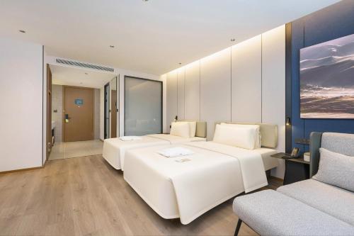 大連市にあるAtour Hotel Dalian Airportのベッド2台とソファが備わるホテルルームです。