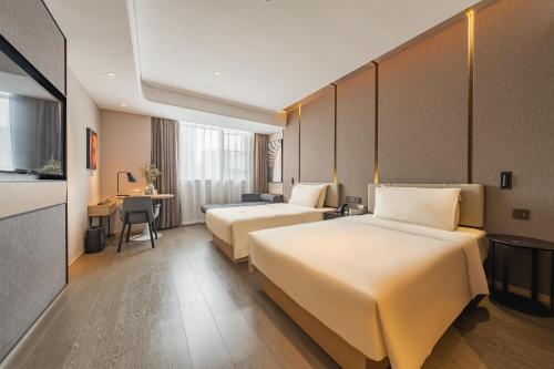 a hotel room with two beds and a desk at Atour Hotel Guangzhou Zhujiang New Town Wuyangtun in Guangzhou