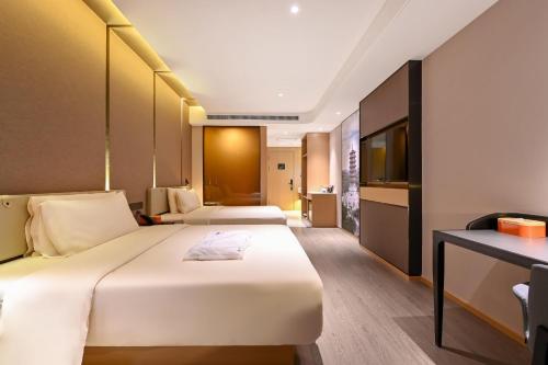 a hotel room with two beds and a desk at Atour Hotel Changchun Automobile Development Zone in Changchun