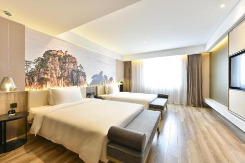a hotel room with two beds and a painting on the wall at Atour Hotel Beijing Chaoyang Park in Beijing