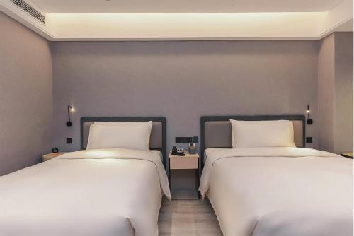 重慶市にあるAtour S Hotel Chongqing Jiefangbei Hongyadong Riverviewのベッド2台が隣同士に設置された部屋です。