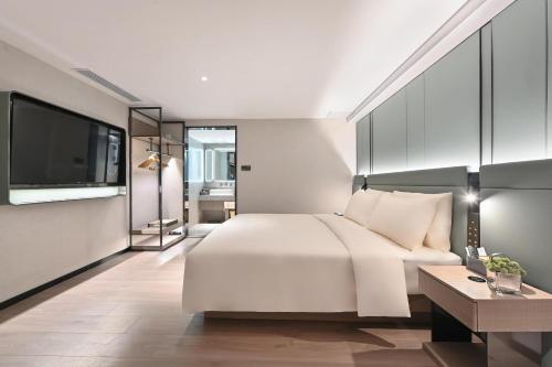 1 dormitorio con 1 cama blanca y TV en Atour S Hotel Beijing Sanlitun Guoan, en Beijing