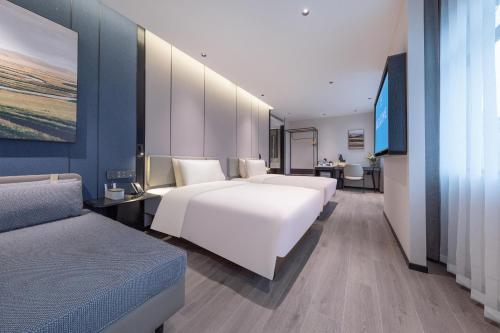 長沙市にあるAtour Hotel Changsha Dongtangのベッド2台とソファがあるホテルの部屋