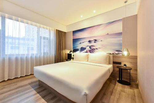 a bedroom with a large bed and a painting on the wall at Atour Hotel Dalian Development Zone Jinma Road in Dalian