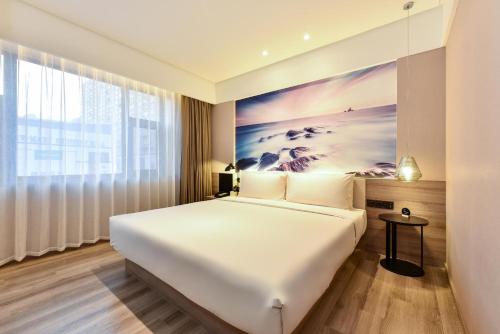 een slaapkamer met een groot bed en een schilderij aan de muur bij Atour Hotel Dalian Development Zone Jinma Road in Dalian