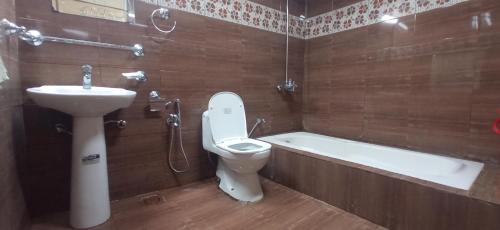 a bathroom with a toilet and a sink and a bath tub at Kashmir Eagle Heights Cottage & Restaurant by LMC in Muzaffarabad