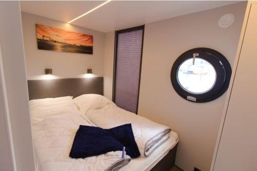 1 dormitorio con 1 cama blanca y ventana en Hausboot Fjord Aries mit Dachterrasse in Schleswig, en Schleswig