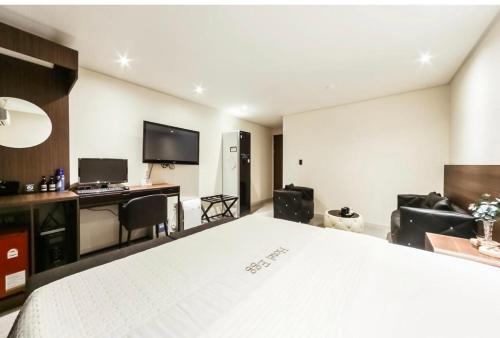 a bedroom with a large white bed and a desk at Hotel Egg in Busan