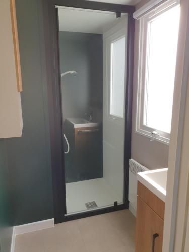 a bathroom with a shower and a sink and a mirror at Camping du Bois Dormant in Saint-Jean-de-Monts
