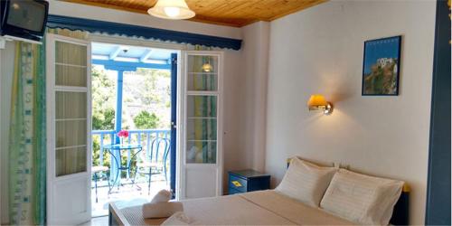 Schlafzimmer mit einem Bett und einer Tür zu einer Terrasse in der Unterkunft Galini Hellenic Hospitality in Patitiri