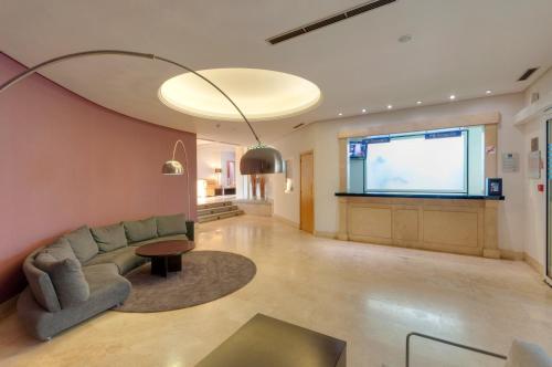 a living room with a couch and a large screen at Gran Hotel Los Angeles in Getafe